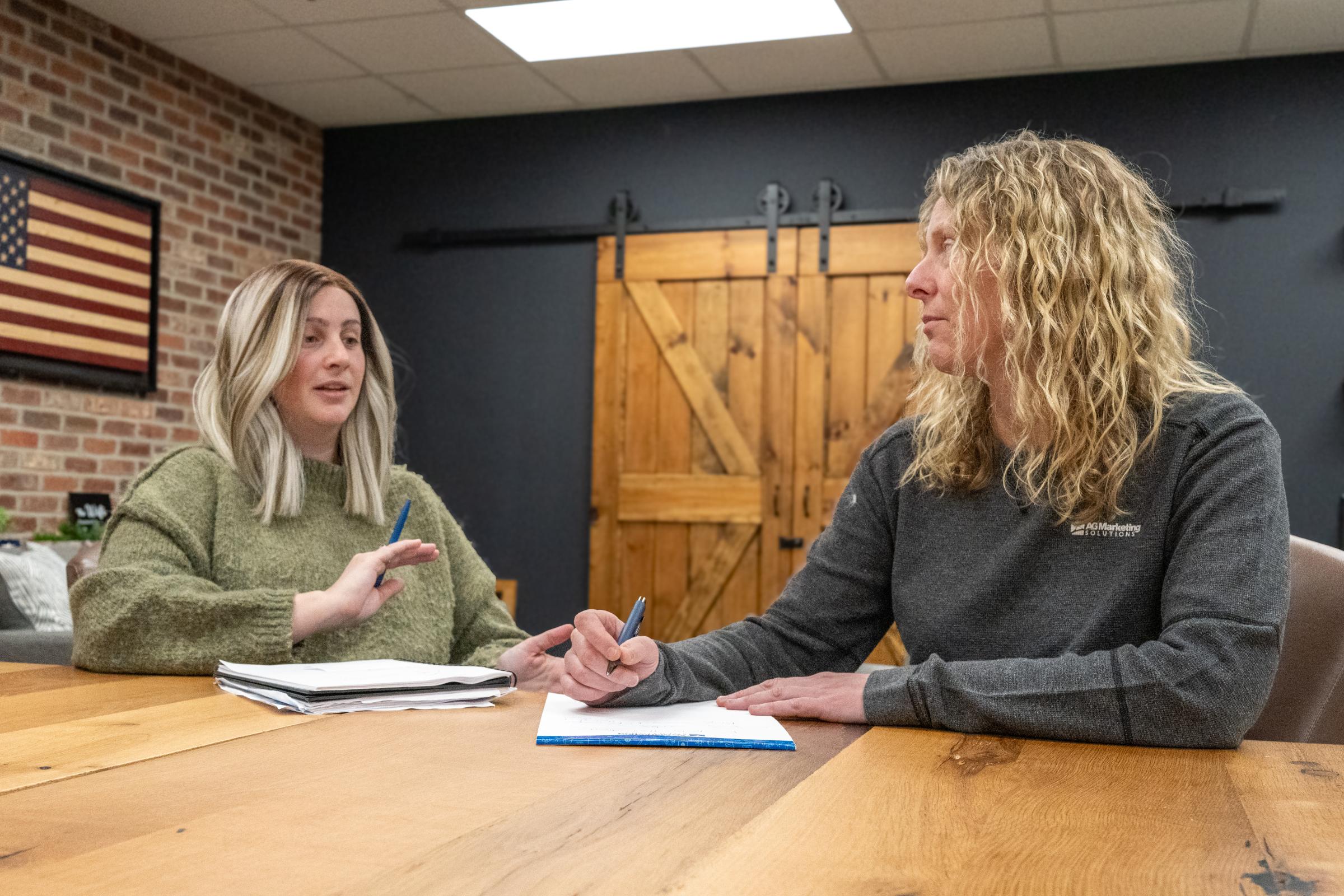 Two people discussing strategy at a table with notes and documents